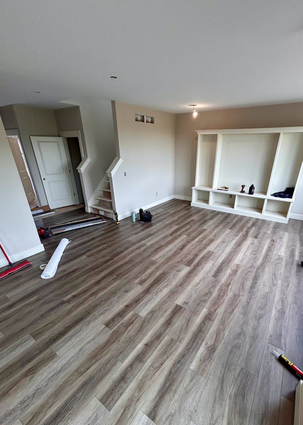 Finished wood-look plank flooring beside entryway storage and stairs.